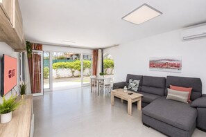 A modern living room with a grey sofa, a coffee table, and a TV on the wall. - GuestReady - Sun Club Hammock Relax (San Bartolomé de Tirajana)