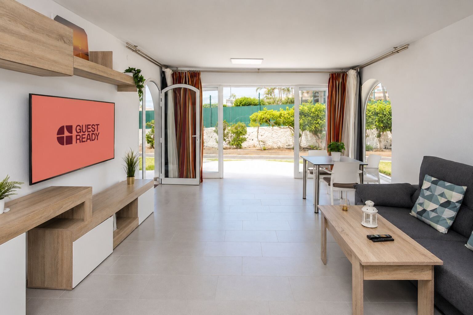Una sala de estar moderna con televisor de pantalla plana, un sofá, una mesa de centro y un comedor.