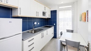 A modern kitchen with white cabinets, a built-in microwave, and a sink. - GuestReady - Sun Club Hammock Relax (San Bartolomé de Tirajana)