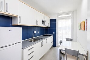 A modern kitchen with white cabinets, a built-in microwave, and a sink. - GuestReady - Sun Club Hammock Relax (San Bartolomé de Tirajana)