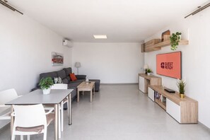A modern living room with a sofa, coffee table, and a dining area with chairs and a table. - GuestReady - Sun Club Hammock Relax (San Bartolomé de Tirajana)