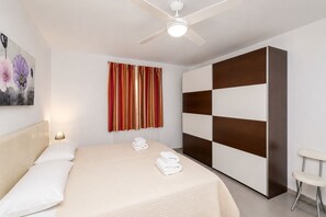 A hotel room with a bed, a wardrobe, a ceiling fan, and a window with curtains. - GuestReady - Sun Club Hammock Relax (San Bartolomé de Tirajana)
