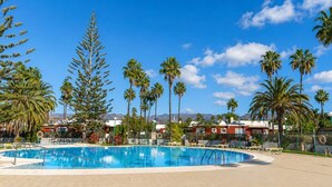 A swimming pool with palm trees and a clear blue sky. - GuestReady - Los Tunos Family Pool (Maspalomas)