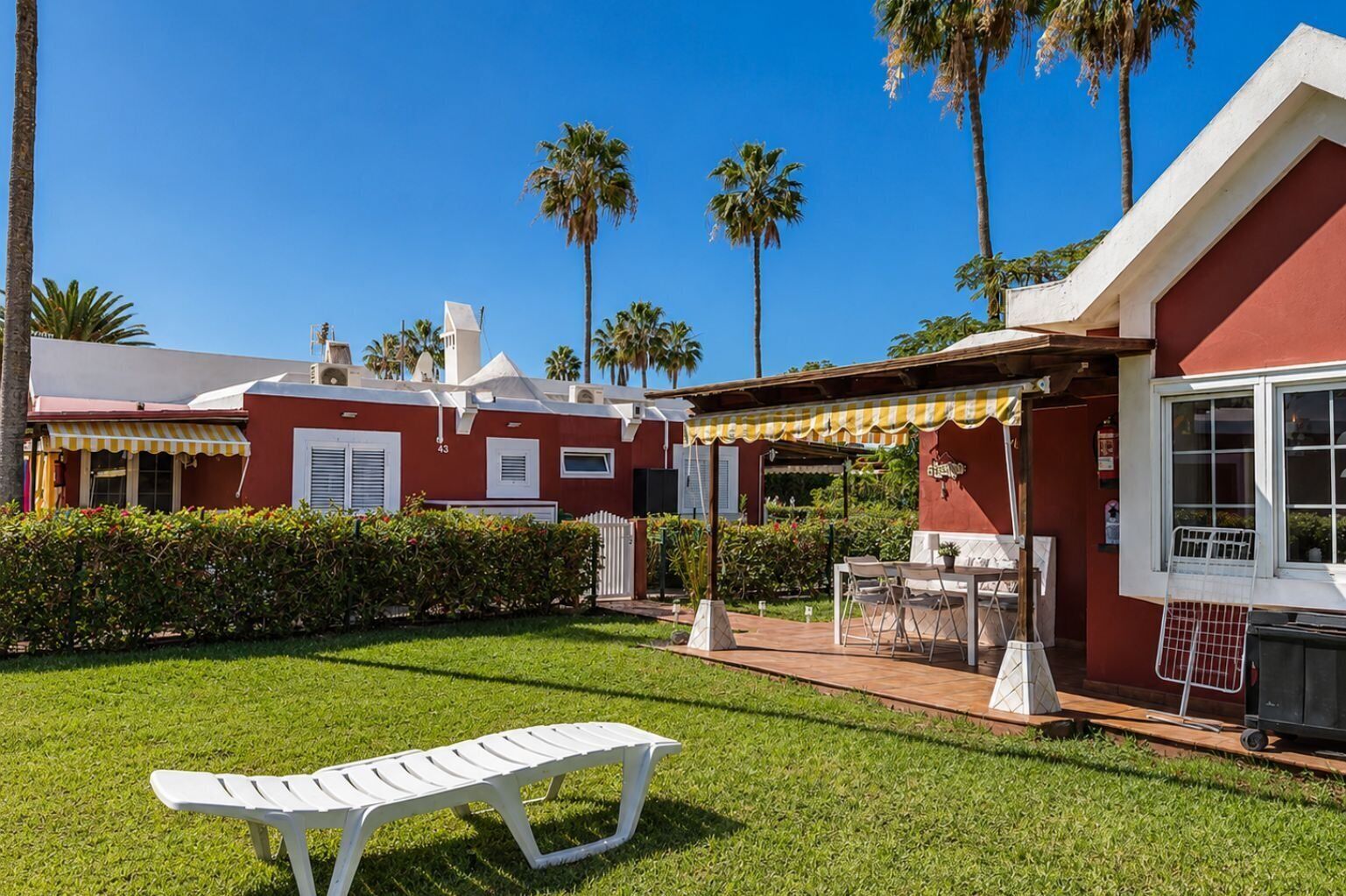 A red building with a patio area, outdoor seating, and a white lounge chair.