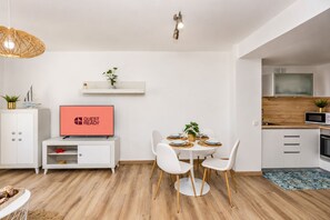 Ein modernes Wohnzimmer mit Essbereich, einer Küche und einem Fernseher, der 'GUEST READY' anzeigt.