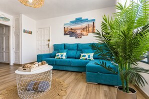 A living room with a blue sofa, a round coffee table, and a potted plant. - GuestReady - Stylish Retreat Steps from the Beach (Corralejo)