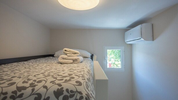 Un dormitorio con cama, ventana y aire acondicionado.