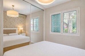 Ein Schlafzimmer mit Bett, Nachttisch, Lampe und einem Fenster mit Rollläden.