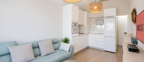 Un apartamento moderno con sofá, una mesa de centro, cocina y sala de estar.