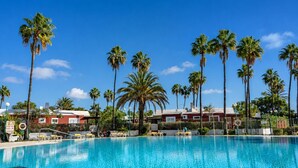 Una piscina rodeada de palmeras y edificios rojos.