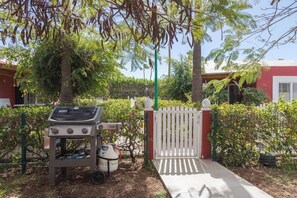 A barbecue grill with a gas tank and a white fence with a gate. - GuestReady - Los Tunos Barbecue and Pool (Maspalomas)