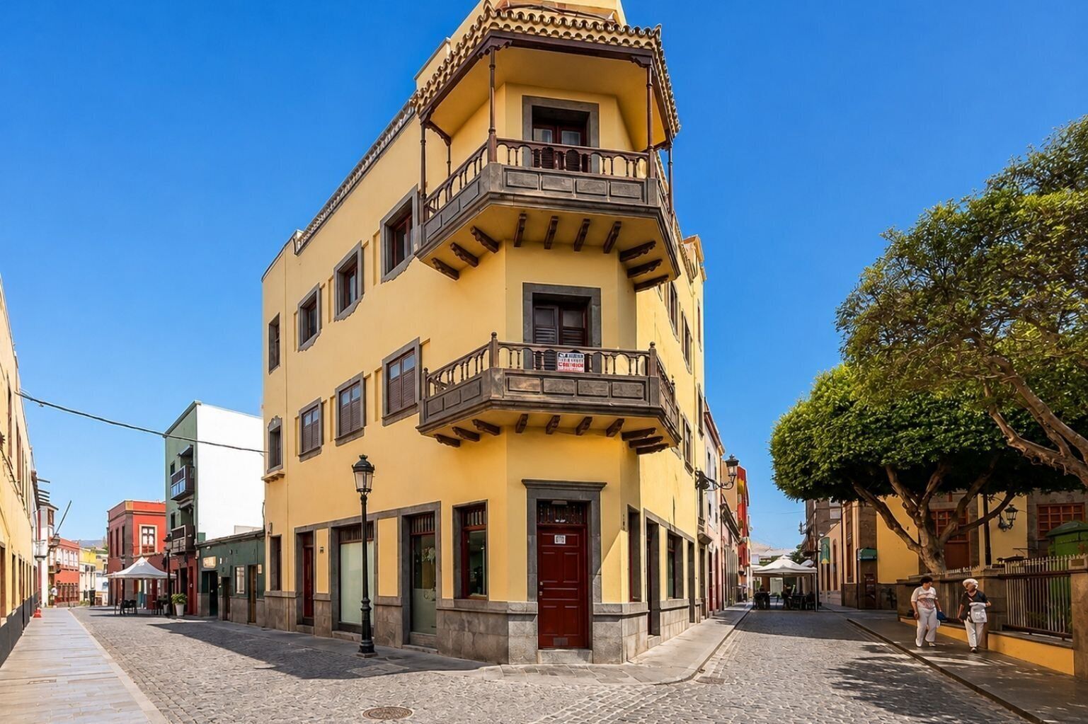 A multi-story building with a red door, balconies, and a cobblestone street.