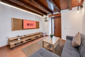 A furnished living room with a sofa, a coffee table, a wooden bench, and a wall-mounted TV displaying 'GUEST READY'.