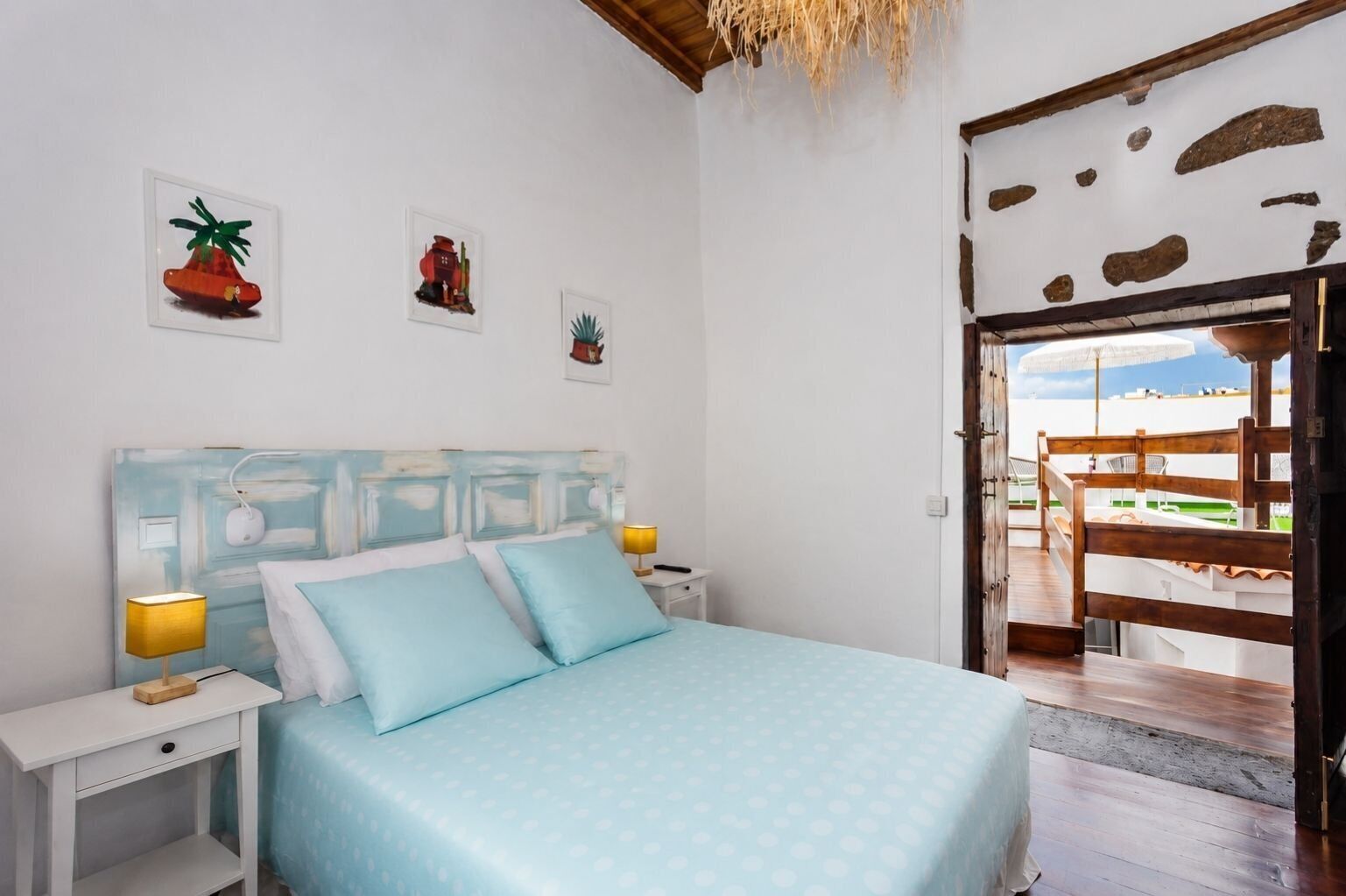 A bedroom with a bed, bedside tables, and a view of the outside.