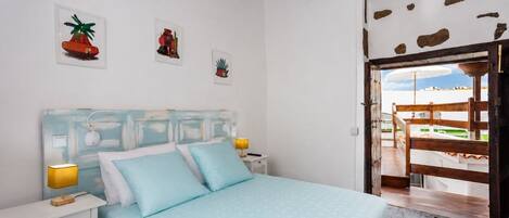 A bedroom with a bed, bedside tables, and a view of the outside.