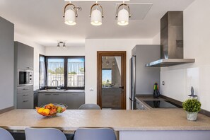 Eine moderne Küche mit einer zentralen Kochinsel, Edelstahlgeräten und Blick durch das Fenster.