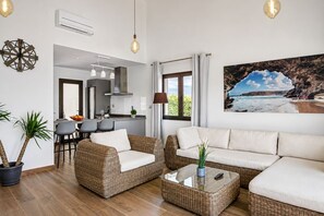 Ein modernes Wohnzimmer mit Korbmöbeln, einem Essbereich und einer Küche.