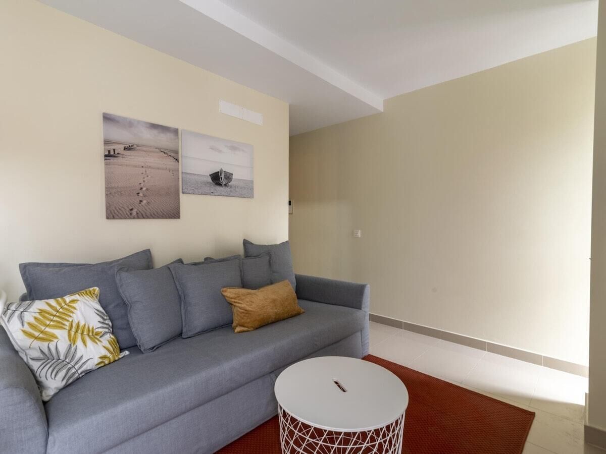 A modern living room with a grey sofa, a round coffee table, and two wall-mounted artworks.