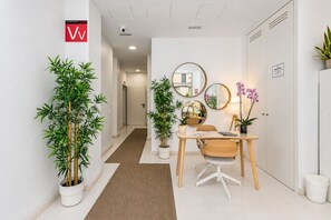 Une chambre d’hôtel moderne équipée d’un bureau, de chaises, de plantes en pot et d’un miroir.