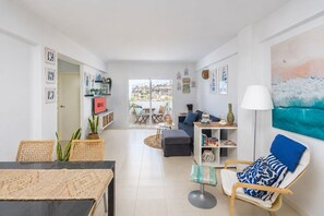 A modern living room with a sofa, a dining table, and chairs. There is a balcony with a view of the city. - GuestReady - La Palmita Agaete with Pool (Agaete)