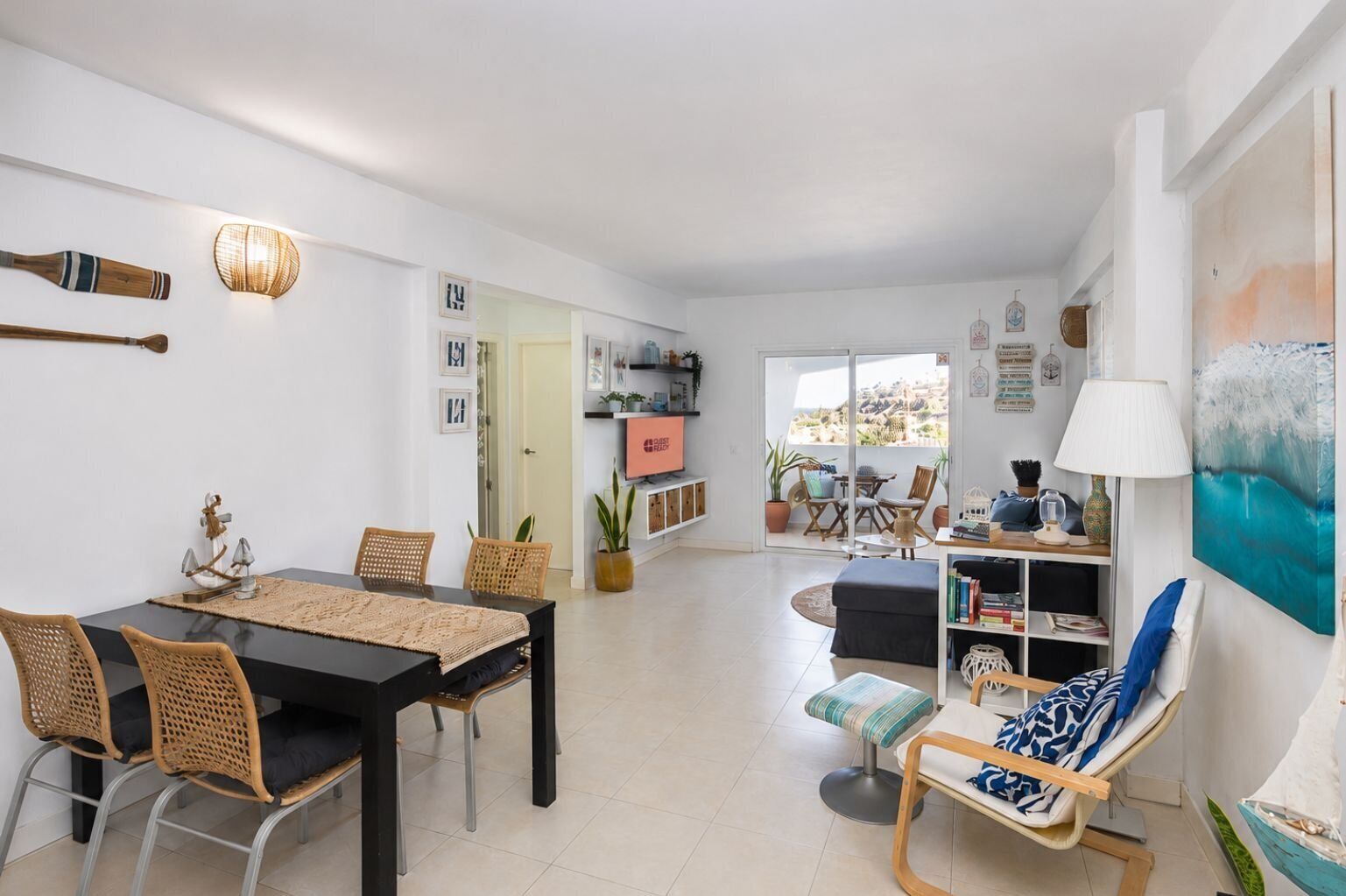 Un salon moderne comprenant un coin repas, un canapé, un téléviseur et un balcon agrémenté de plantes.