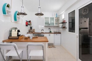 A compact kitchen with a central island, white cabinetry, and a built-in dishwasher.