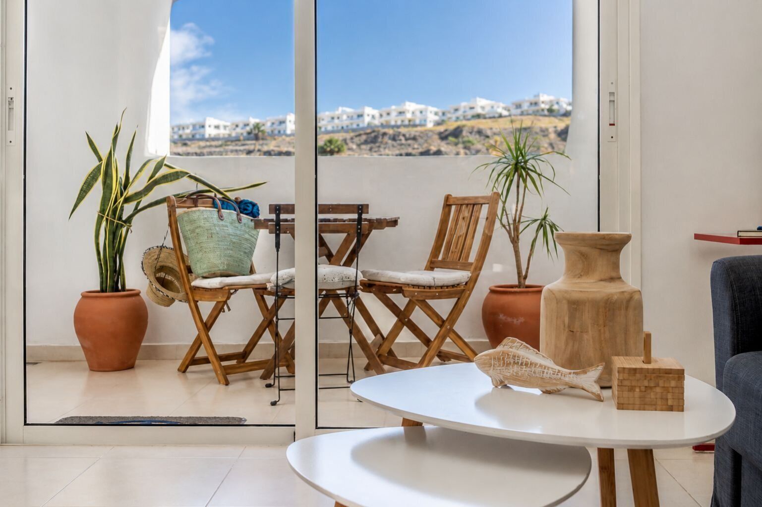 Un soggiorno moderno con un balcone, mobili in legno e piante in vaso.