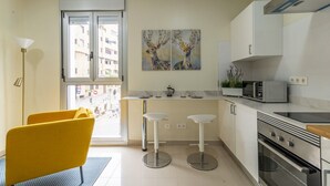 Una cucina moderna con una finestra, due sgabelli da bar, un forno a microonde e un fornello.