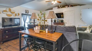 A living room with a wooden table, two bar stools, a ceiling fan, a television, and a couch. - 6 Mi to Town! Trinity Retreat w/ Yard (Trinity)
