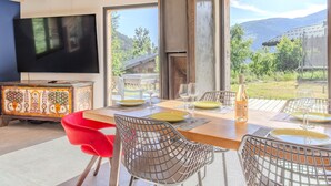 A dining area with a wooden table, metal chairs, and a television in the background.