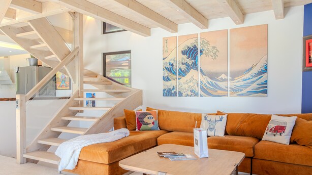 A modern living room with a wooden staircase, a sectional sofa, and a coffee table.