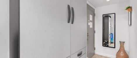 A hallway with grey wardrobe, a mirror, a vase, and a door.