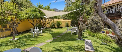 Un jardín bien cuidado con un patio, mobiliario exterior y diversas plantas.