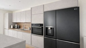 A modern kitchen with a built-in oven, a water dispenser, and a stainless steel refrigerator. - Villa Bartholdi – House & Garden in Holtzheim (Holtzheim)
