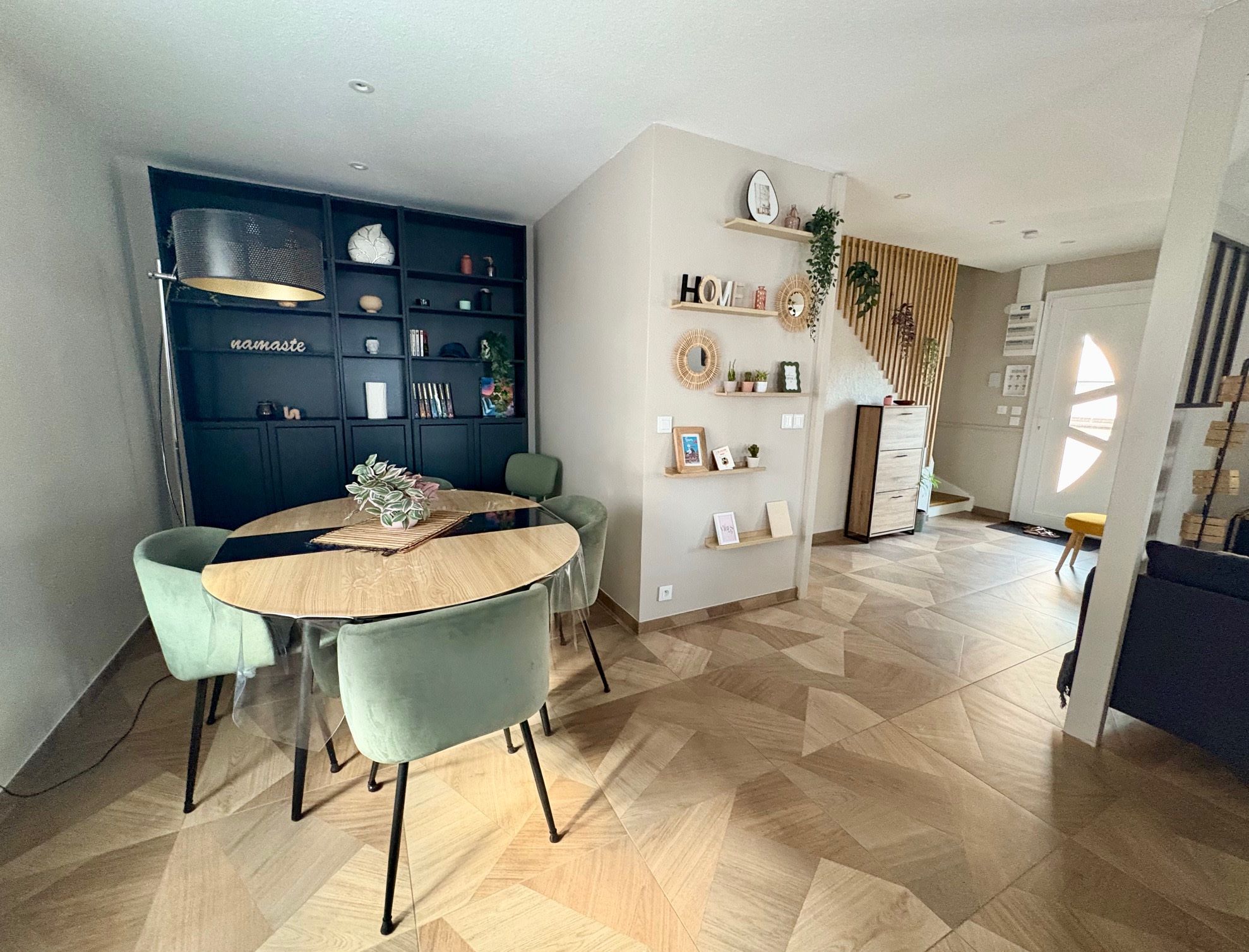 A modern kitchen with a dining area, featuring a round table, two chairs, and a built-in bookshelf.