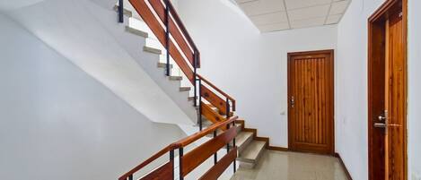 A staircase with wooden handrails and a door with a number plate.