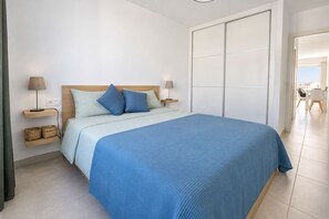 A bedroom with a bed, bedside tables, and a wardrobe. - GuestReady - Senator Terrace Retreat (Costa Teguise)