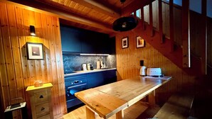 Un intérieur en bois comprenant un coin cuisine, une table à manger et un petit panier pour animaux de compagnie.
