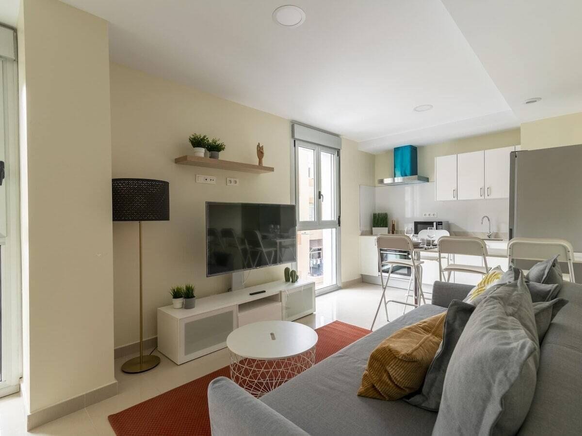 A modern living room with a sofa, TV, and a small white table.