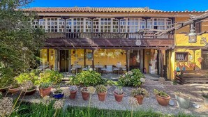 A building with a tiled roof, a balcony, and outdoor seating. - GuestReady - Las Calas 7 Suite w/ terrace Gardenia (Las Palmas de Gran Canaria)