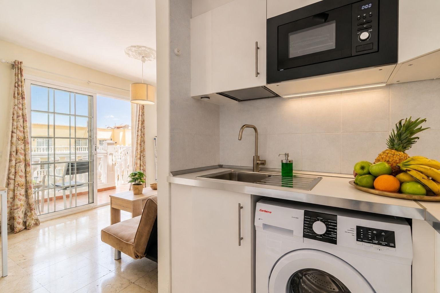 A compact kitchen with a washing machine, a microwave, and a sink.