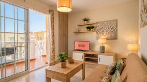 Een moderne woonkamer met een bank, salontafel, televisie en een balkon met uitzicht.