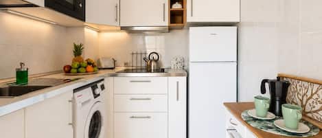 A modern kitchen with a washing machine, a microwave, a toaster, and a coffee maker.