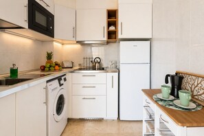 A modern kitchen with a washing machine, a microwave, a toaster, and a coffee maker. - GuestReady - Bright Stay with Balcony (Caleta de Fuste)
