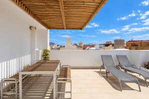 A rooftop terrace with a wooden pergola, a table, and two lounge chairs. - GuestReady - 02A Livian Suites Int 2 Pax (Las Palmas de Gran Canaria)