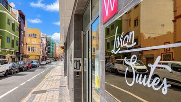 A street view with a building featuring a prominent 'W' sign and the name 'Lilian Suites' in cursive.