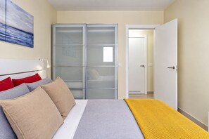Ein Schlafzimmer mit einem Bett, einem Kleiderschrank und einer Tür zu einem weiteren Raum.