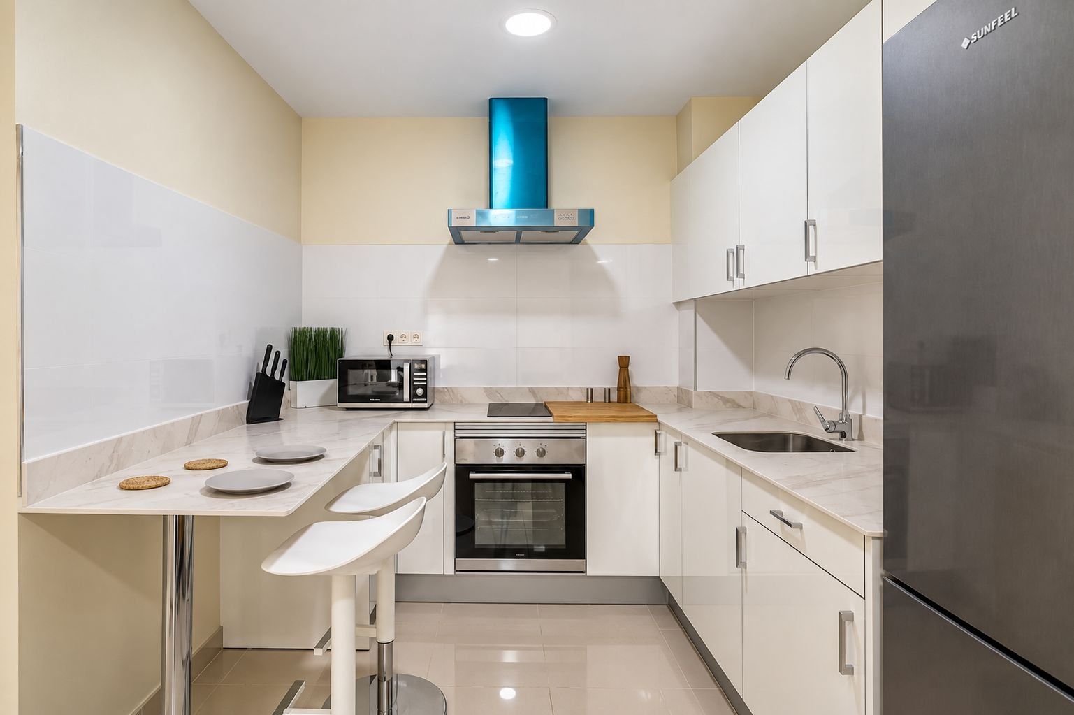 A compact kitchen with white cabinets, a stainless steel refrigerator, a microwave, and an oven.
