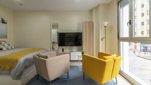 Hotelkamer met een bed, televisie, bureau, stoel en groot raam.