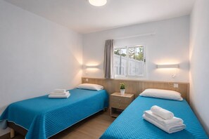 A hotel room with two single beds, a small bedside table with a plant, and a window with curtains. - GuestReady - Alemania Villa Garden (San Bartolomé de Tirajana)